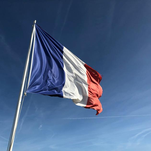 Auf dem Bild ist die französische Flagge in den Farben blau, weiß und rot vor einem blauen Himmel zu sehen