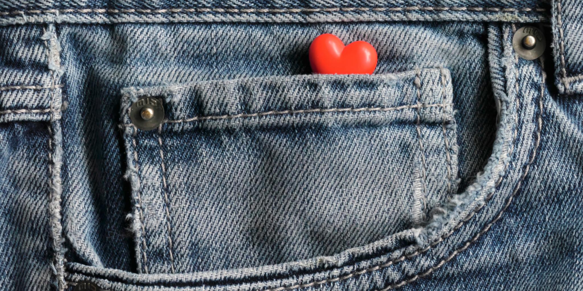 Rotes Herz in einer kleinen Vordertasche einer blauen Jeans.