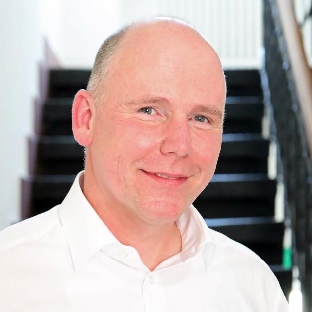 Auf dem Foto zu sehen ist Torsten Wahl vor einer Treppe stehend